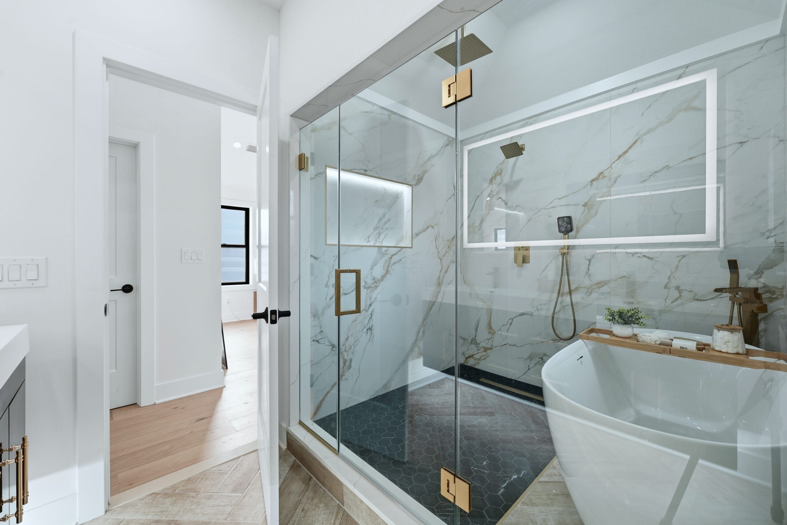 Primary spa bathroom with a Calacatta marble walk-in shower, freestanding soaking tub, and brushed gold fixtures