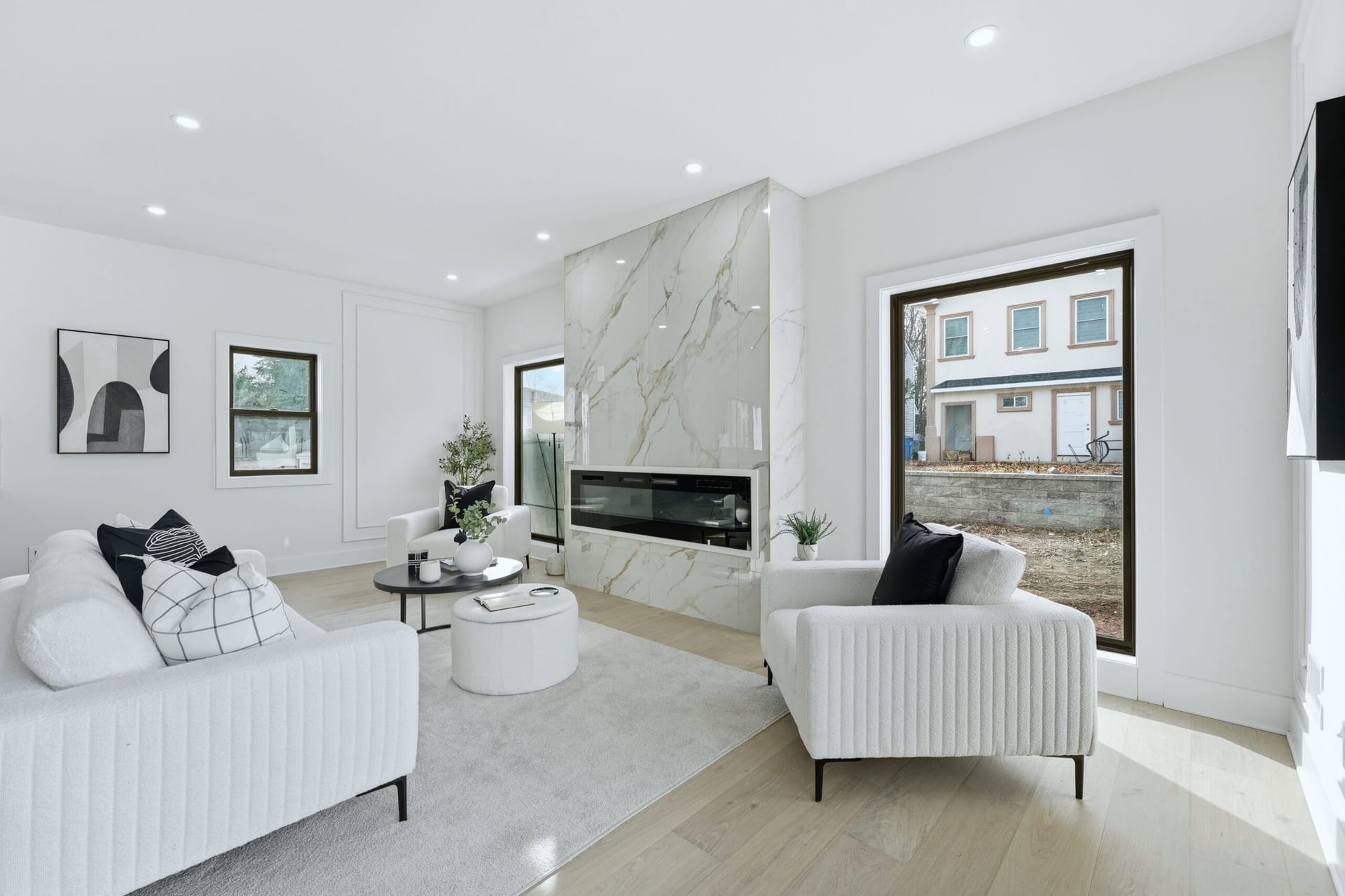 Sunlit living room with a full-height Calacatta marble fireplace surround and white bouclé seating