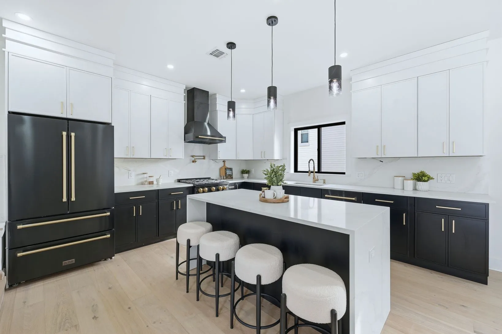 Renovated chef’s kitchen with black shaker cabinetry, brushed gold hardware, a waterfall quartz island, and bouclé bar stools