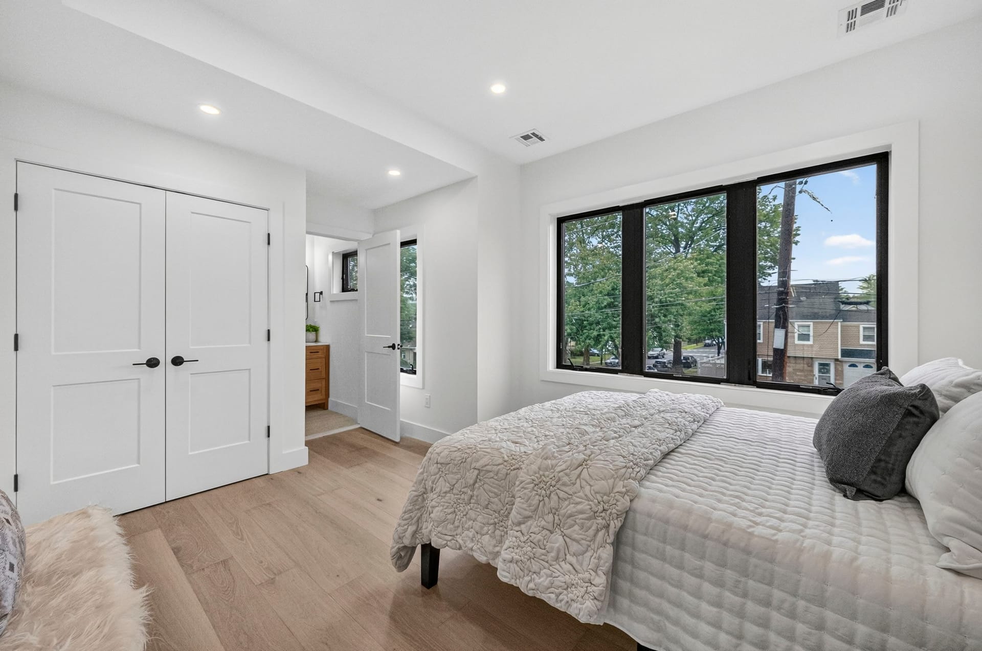 Bedroom with double closet doors and a large window overlooking the street