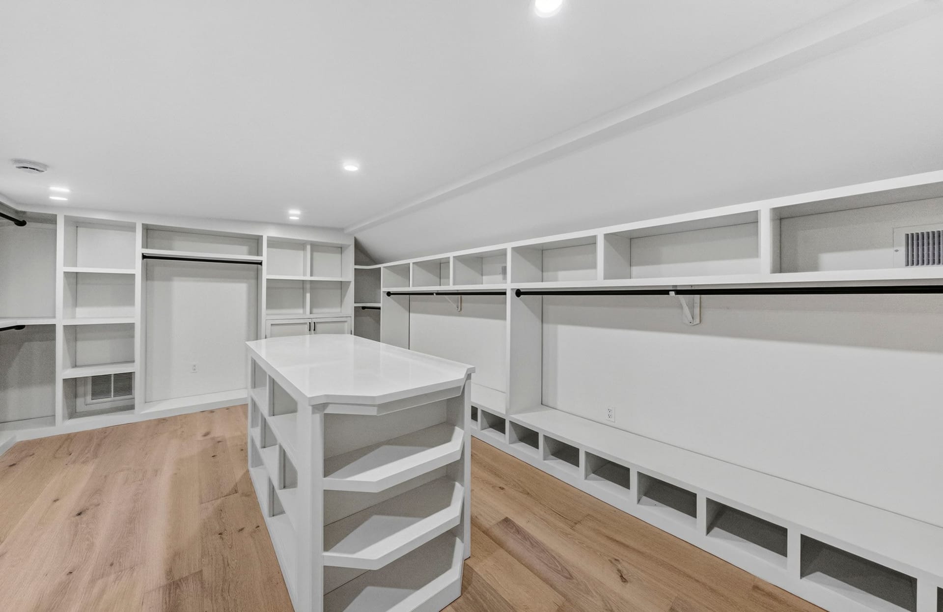 Walk-in closet with a center island and built-in shelving under a sloped ceiling