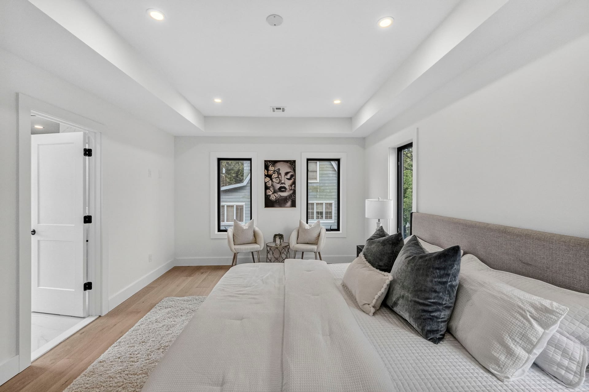 Primary bedroom seating area with a tray ceiling and framed artwork