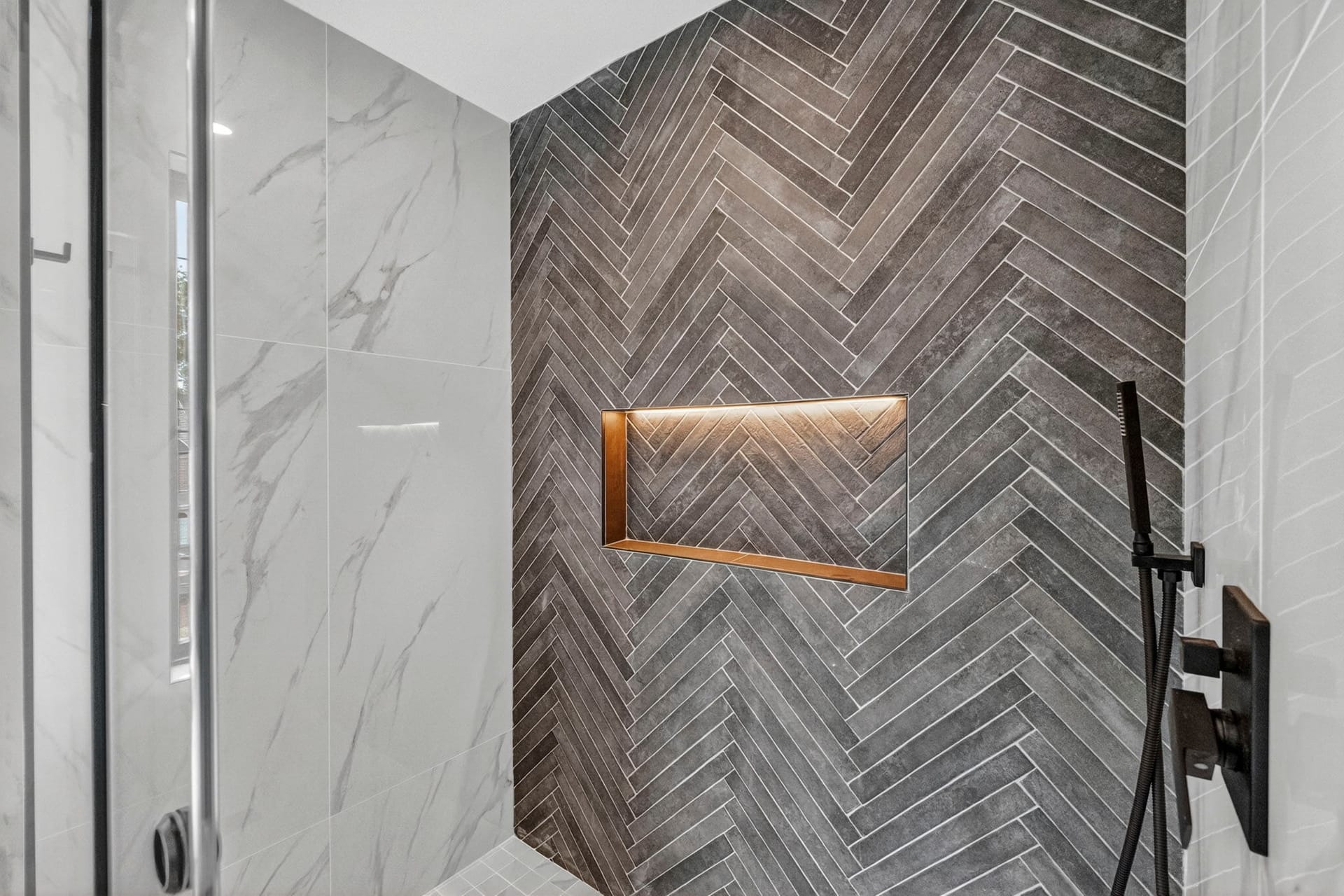 Detail of the herringbone tile shower with a wood accent niche