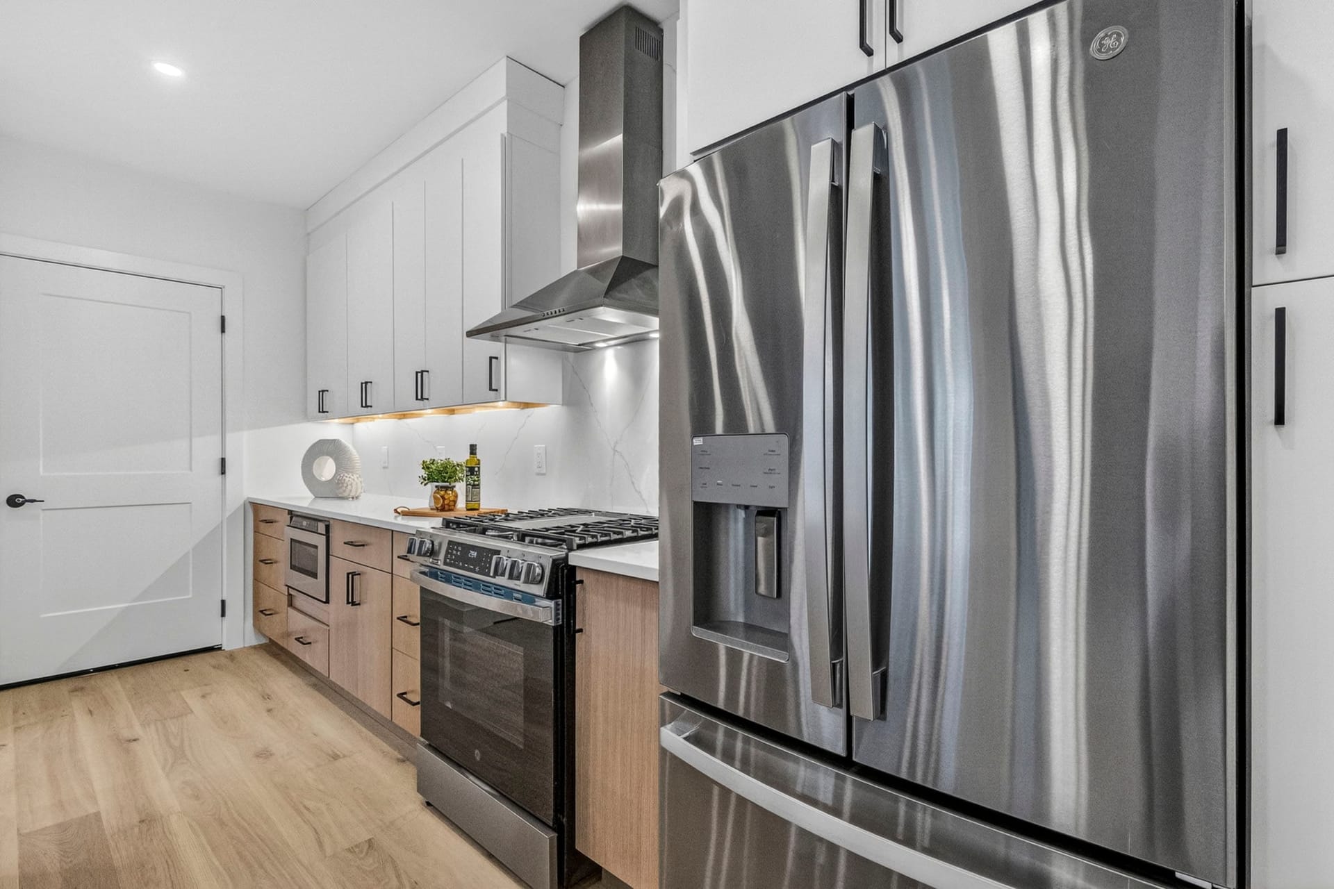 Kitchen cooking area with a gas range, subway tile backsplash, and stainless refrigerator