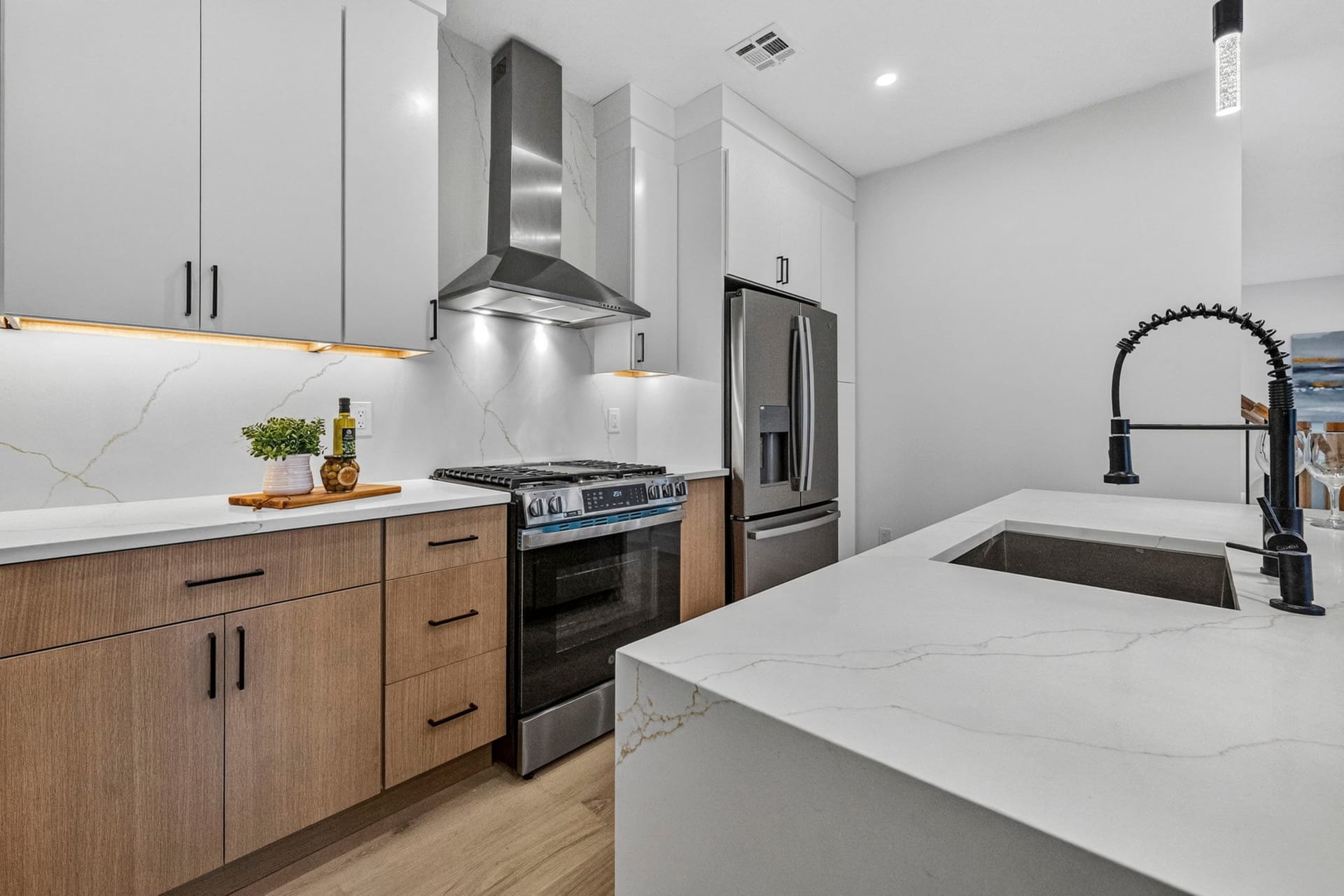 Kitchen island with a matte black faucet and quartz waterfall countertop