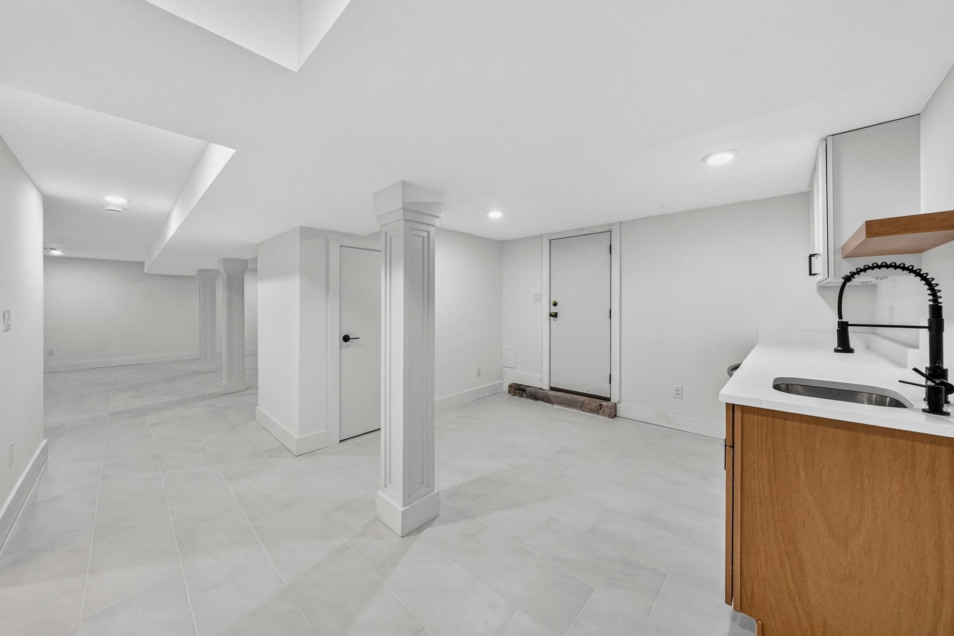 Basement wet bar sink area with a columned archway