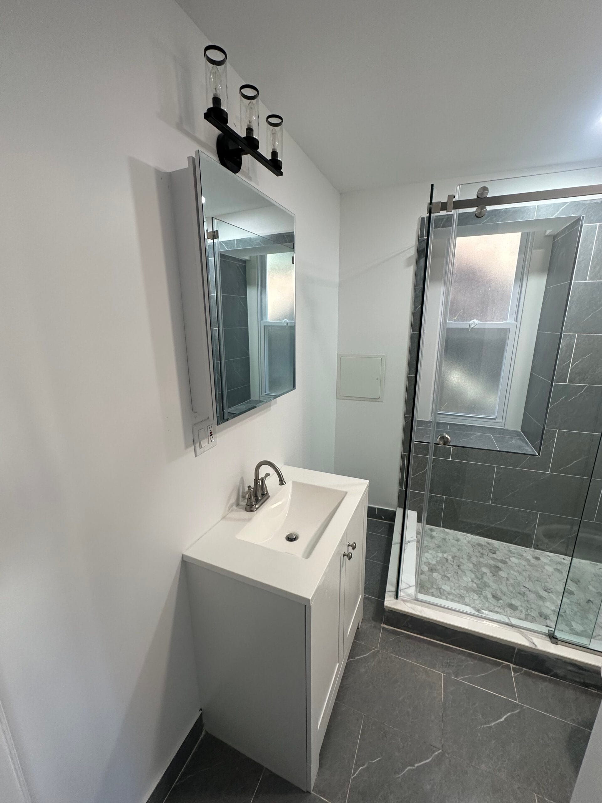 Renovated Fairview bathroom with grey stone-look tile and a sliding glass shower